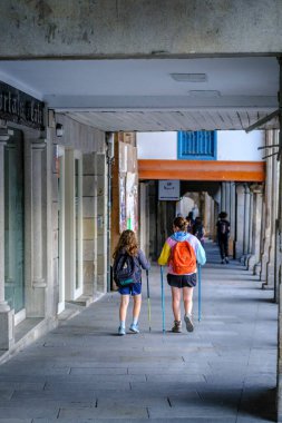 PONTEVEDRA, 8 Temmuz 2022: Köyün tarihi merkezindeki kaldırımlı caddelerden birinde yürüyen hacılar.