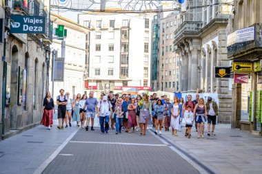 PONTEVEDRA, İSPAN - 6 Ağustos 2022: Birçok turist şehir sokaklarından birinde rehberlerini takip ederek yürüyor.