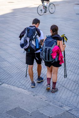 PONTEVEDRA, İSPAN - 6 Ağustos 2022: Bir çift hacı Camino de Santiago 'nun bir parçası olan şehrin sokaklarından birinden geçiyor.
