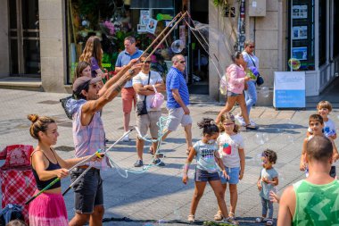 PONTEVEDRA, SPAIN - 6 Ağustos 2022: Birkaç sokak göstericisi, dev sabun baloncuklarıyla oynayarak seyircileri eğlendiriyor.