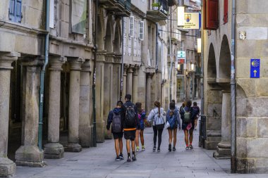 PONTEVEDRA, SPAIN - 10 Ağustos 2022: Camino de Santiago 'daki bazı hacılar şehrin sokaklarından birinde granit kaldırımlarla yürüyorlar.