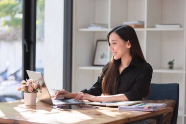 Smartphone ve Laptop 'la çalışma alanında çalışan güzel bir genç kadın.