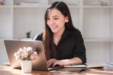 Smartphone ve Laptop 'la çalışma alanında çalışan güzel bir genç kadın.