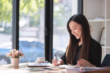 Smartphone ve Laptop 'la çalışma alanında çalışan güzel bir genç kadın.