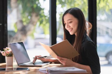 Smartphone ve Laptop 'la çalışma alanında çalışan güzel bir genç kadın.