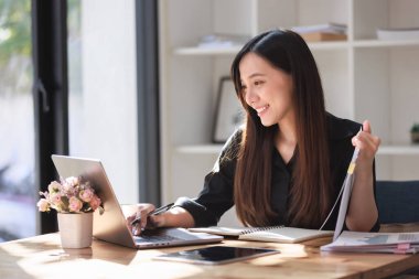 Smartphone ve Laptop 'la çalışma alanında çalışan güzel bir genç kadın.