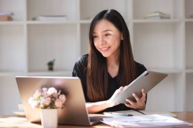 Smartphone ve Laptop 'la çalışma alanında çalışan güzel bir genç kadın.