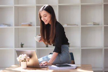 Smartphone ve Laptop 'la çalışma alanında çalışan güzel bir genç kadın.