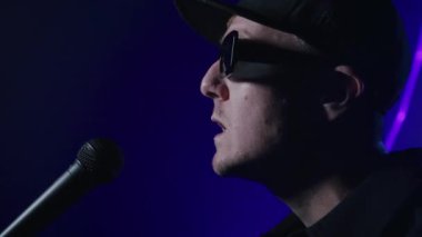 Karanlık bir lazer arkaplanda şarkı söyleyen bir rap sanatçısının yakın çekimi. 4k yüksek çözünürlüklü görüntü. 