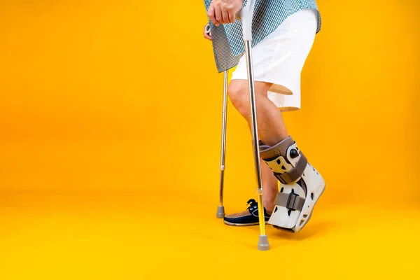 Portrait retired asian senior man walking with crutches in ankle brace , Health problems medical concept.