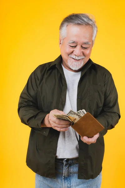 Traveling retired asian elderly man happy holding US dollars money .