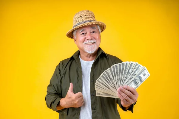 Traveling retired asian elderly man happy holding US dollars money .