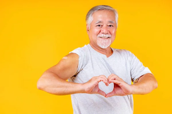 old man showing arm with plaster fully vaccinated or booster vaccinated able to travel to various countries , elderly man fully vaccinated or booster vaccinated show heart shape on hand.
