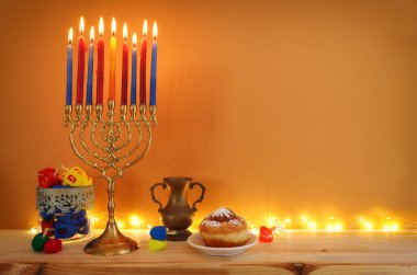 Menorah (geleneksel şamdan), donut ve mumlarla Yahudi bayramı Hanuka arkaplanının dini görüntüsü