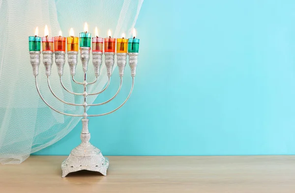 Image of jewish holiday Hanukkah with menorah (traditional candelabra) and colorful oil candles