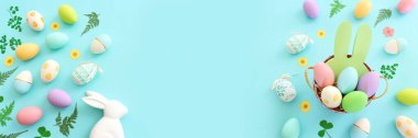 Cute bunny next to easter colorful eggs over blue pastel background