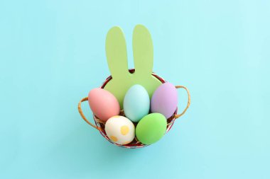 Cute bunny next to easter colorful eggs over blue pastel background