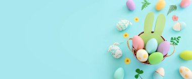 Cute bunny next to easter colorful eggs over blue pastel background
