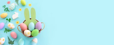 Cute bunny next to easter colorful eggs over blue pastel background