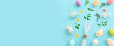 Cute bunny next to easter colorful eggs over blue pastel background