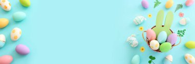 Cute bunny next to easter colorful eggs over blue pastel background