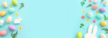 Cute bunny next to easter colorful eggs over blue pastel background