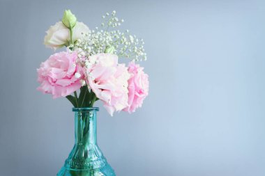 Mavi vazodaki narin lisianthus çiçeklerinin üst görünümü pastel arkaplan üzerinde