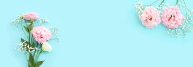 Pastel mavi arkaplan üzerinde narin lisianthus çiçeklerinin üst görünümü