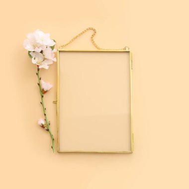 Badem çiçeği çiçeklerinin üst manzarası ve sarı pastel arkaplan üzerinde altın renkli boş çerçeve. Model oluşturmak için, alanı kopyala