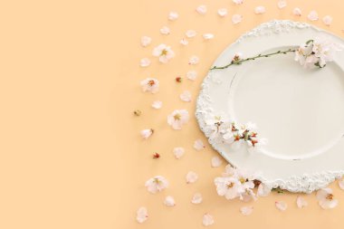 Bahar kiraz ağacı çiçeklerinin üzerindeki beyaz antika boş tabağın üst görüntüsü. Düz yatıyordu