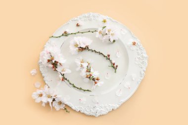 Bahar kiraz ağacı çiçeklerinin üzerindeki beyaz antika boş tabağın üst görüntüsü. Düz yatıyordu