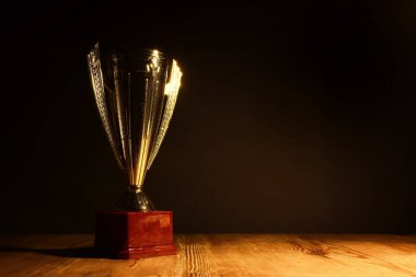 düşük anahtar görüntü Trophy üzerinde ahşap masa ve koyu arka plan