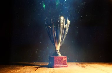düşük anahtar görüntü Trophy üzerinde ahşap masa ve soyut glitter ışıkları ile koyu arka plan