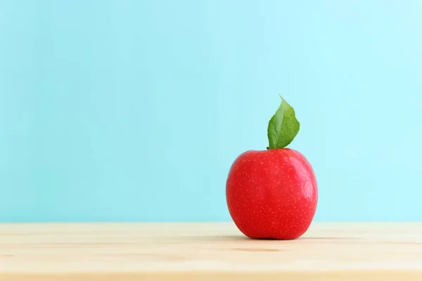木制桌子上放一个新鲜的红苹果 蓝色背景 — 图库照片