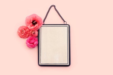 Pembe çiçeklerin üst görüntüsü ve pastel arkaplan üzerinde siyah zarif boş çerçeve. Model oluşturmak için, alanı kopyala