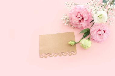 Pembe çiçeklerin üst görünüm kompozisyonu ve pastel arkaplan üzerine boş nota