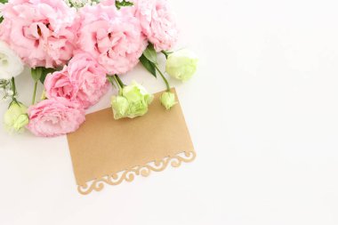 Pembe çiçeklerin üst görünüm kompozisyonu ve beyaz arkaplan üzerine boş not