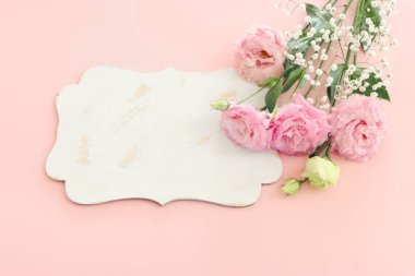 Üst görüntü pembe çiçek kompozisyonu ve pastel arkaplan üzerinde boş tahta