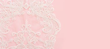 Pembe zemin üzerinde beyaz, narin dantel kumaş