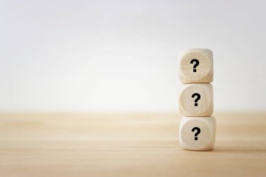 Beyaz arka planda soru işaretleri olan tahta küpler.