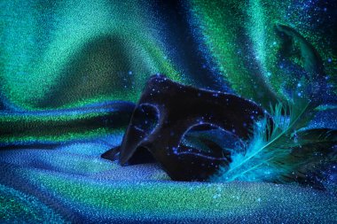 Mavi ve yeşil arkaplan üzerine zarif ve narin siyah Venedik maskesi.