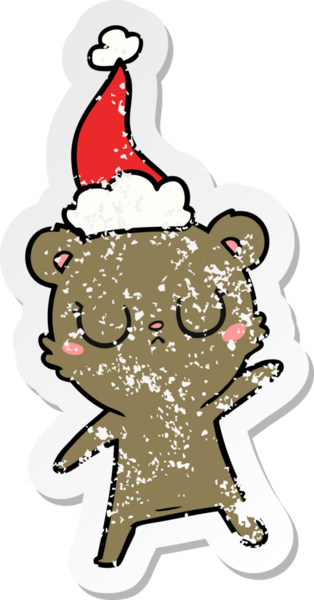 Huzurlu bir el, bir insan tarafından çizilmiş Noel Baba şapkası takan bir ayı çıkartması çizmiş.