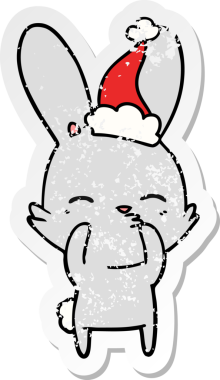 Meraklı tavşanlı el, insan tarafından çizilmiş Noel Baba şapkası giymiş bir karikatür çizmiş.