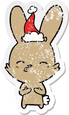 Meraklı tavşanlı el, insan tarafından çizilmiş Noel Baba şapkası giymiş bir karikatür çizmiş.