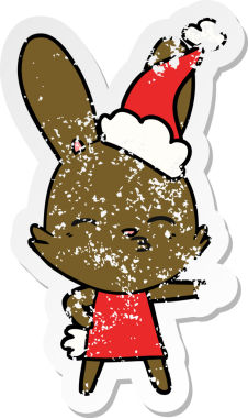 Meraklı tavşanlı el, insan tarafından çizilmiş Noel Baba şapkası giymiş bir karikatür çizmiş.