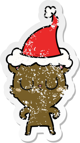 Huzurlu bir el, bir insan tarafından çizilmiş Noel Baba şapkası takan bir ayı çıkartması çizmiş.