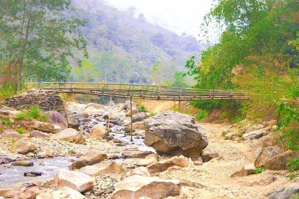 Large Boulder Rocks and river streams flowing in a mountain valley against hill, forest, and a Bamboo bridge in the background. Rangbang river mountain valley. Tabakoshi West Bengal India