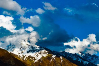 Mavi gökyüzü ve yüzen bulutlarla karla kaplı dağ tepesi. Dramatik Doğa manzarası. Yungthum Vadisi Sikkim Hindistan Güney Asya Pasifik