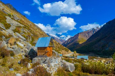 Mavi gökyüzüne karşı bir dağ vadisinde küçük bir kabin odası ve arka planda uçan bulutlar. Chitkul Köyü Himachal Pradesh Hindistan Güney Asya Pasifik