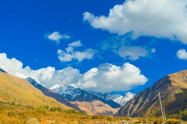Himalaya Dağ Vadisi 'nde gün batımında mavi gökyüzüne ve arka planda uçan bulutlara karşı.